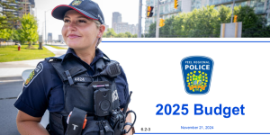 Police officer in community standing in front of the banner of the 2025 Peel Region Police Budget