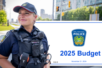 Police officer in community standing in front of the banner of the 2025 Peel Region Police Budget